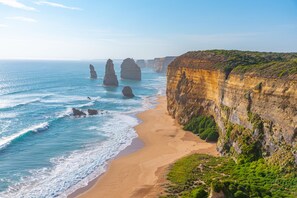 Un paysage côtier avec des falaises, une plage de sable et l’océan.