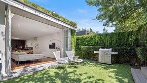 Un patio extérieur moderne avec un canapé blanc, des chaises blanches et un barbecue.