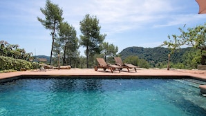 A clear blue pool with lounge chairs and a view of a forested hill. - Nature & Tranquility only 25km from Barcelona (Torrelles de Llobregat)