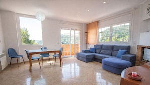 A spacious living room with a large sectional sofa, a dining table with chairs, and a fireplace. - Nature & Tranquility only 25km from Barcelona (Torrelles de Llobregat)