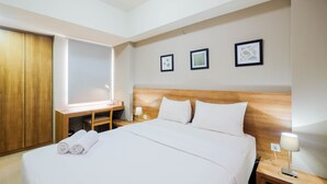 A hotel room with a large bed, a desk, and a TV.
