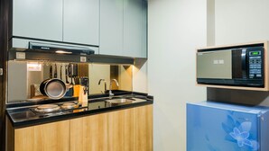 A modern kitchen with wooden cabinets, a black countertop, a sink, and a microwave.