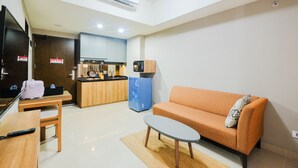 A compact living space with a kitchenette, a sofa, a small table, and a TV.