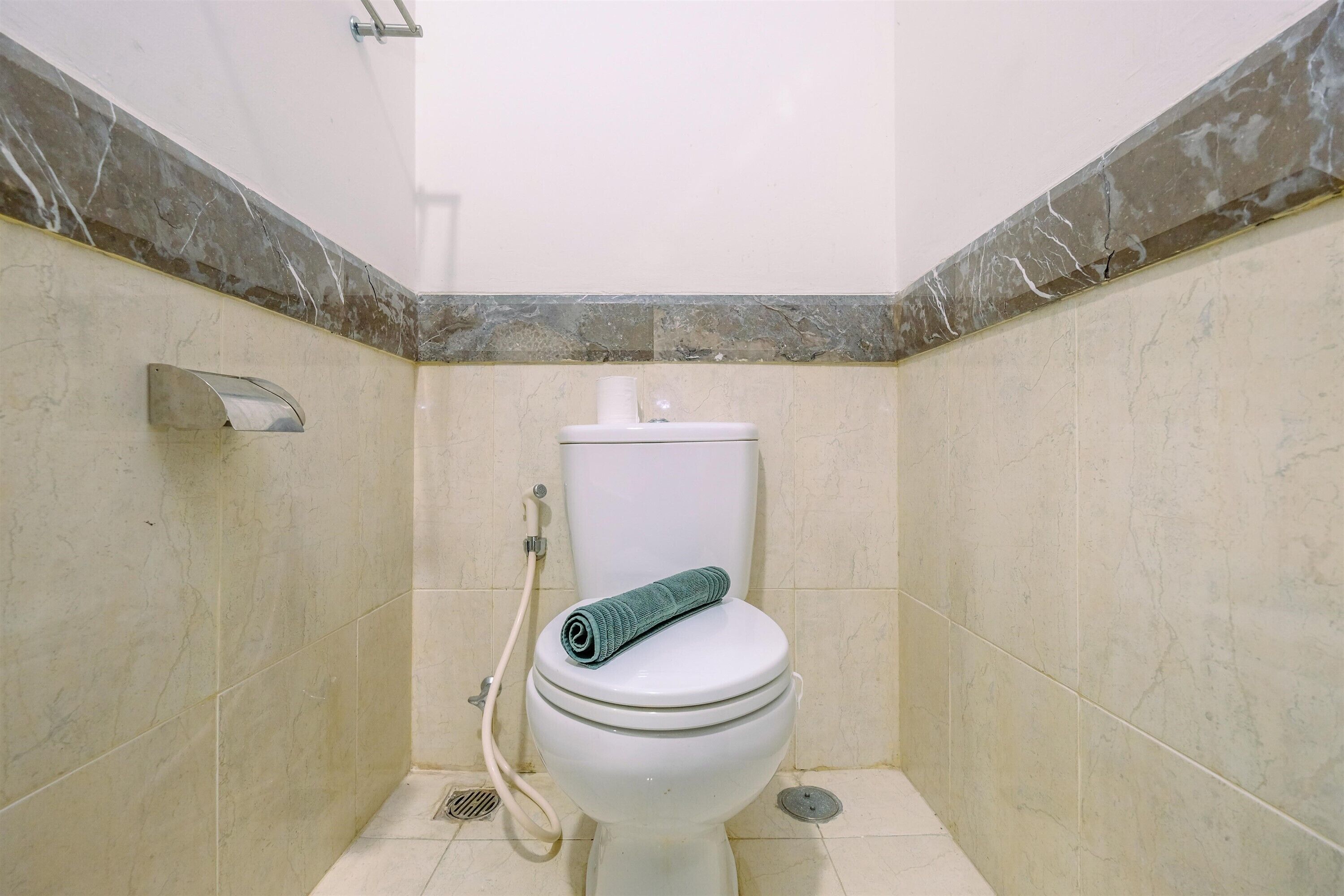 Ein Badezimmer mit Toilette, Dusche und einer Wand mit Marmorplatten.