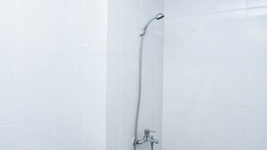 Doccia con soffione a mano e rubinetto a parete, in un bagno piastrellato.