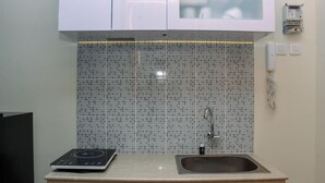 Une cuisine équipée d’une plaque de cuisson à induction intégrée, d’un évier et d’un crédence carrelée.