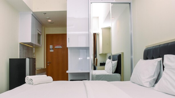 Une chambre d’hôtel comprenant un lit, une armoire, un miroir et une kitchenette.