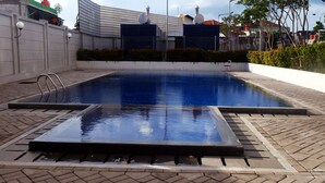 A rectangular swimming pool with a diving board and a ladder, surrounded by a brick walkway.
