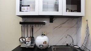 A kitchen with a black countertop, a sink, and a white appliance with a sticker.