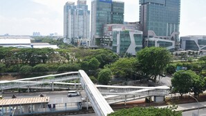 A modern urban area with high-rise buildings, a pedestrian bridge, and greenery.