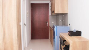 Une cuisine de taille réduite, dotée de meubles de rangement en bois, d’un réfrigérateur, d’un évier et d’un téléphone.