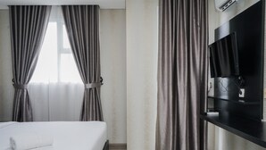 A hotel room with a bed, curtains, a TV, and a wall-mounted shelf. - Nice And Cozy Studio At Bintaro Icon Apartment (South Tangerang)