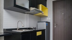A modern kitchen with a black countertop, stainless steel sink, and a built-in oven. - Nice And Cozy Studio At Bintaro Icon Apartment (South Tangerang)