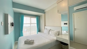 Una habitación de hotel con cama, escritorio, espejo, armario y equipo de aire acondicionado.