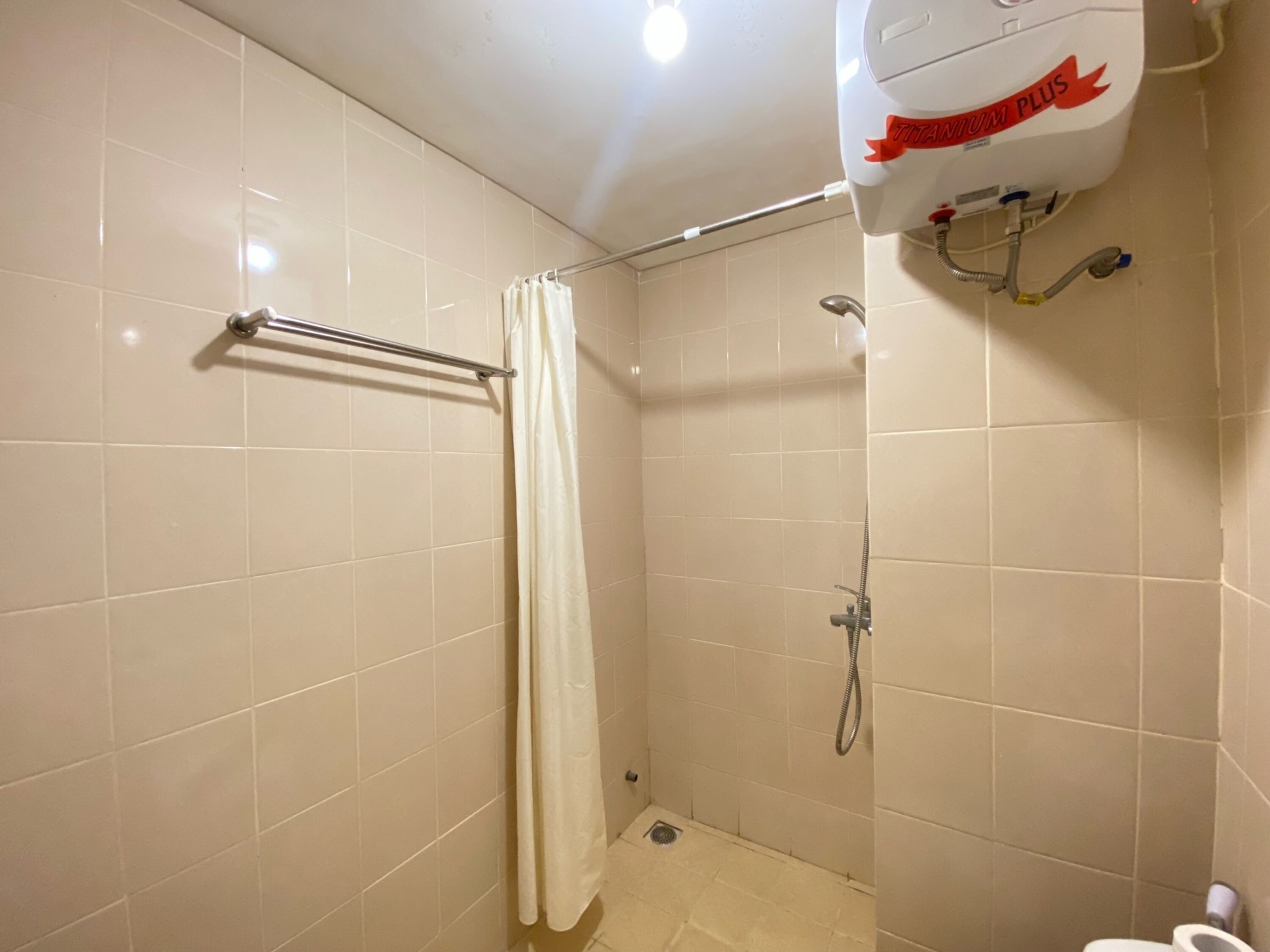 A small, tiled bathroom with a shower, a toilet, and a hand dryer.