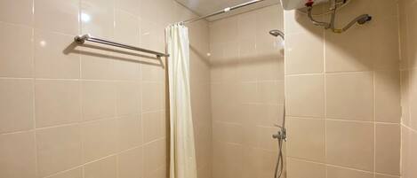 A small, tiled bathroom with a shower, a toilet, and a hand dryer.