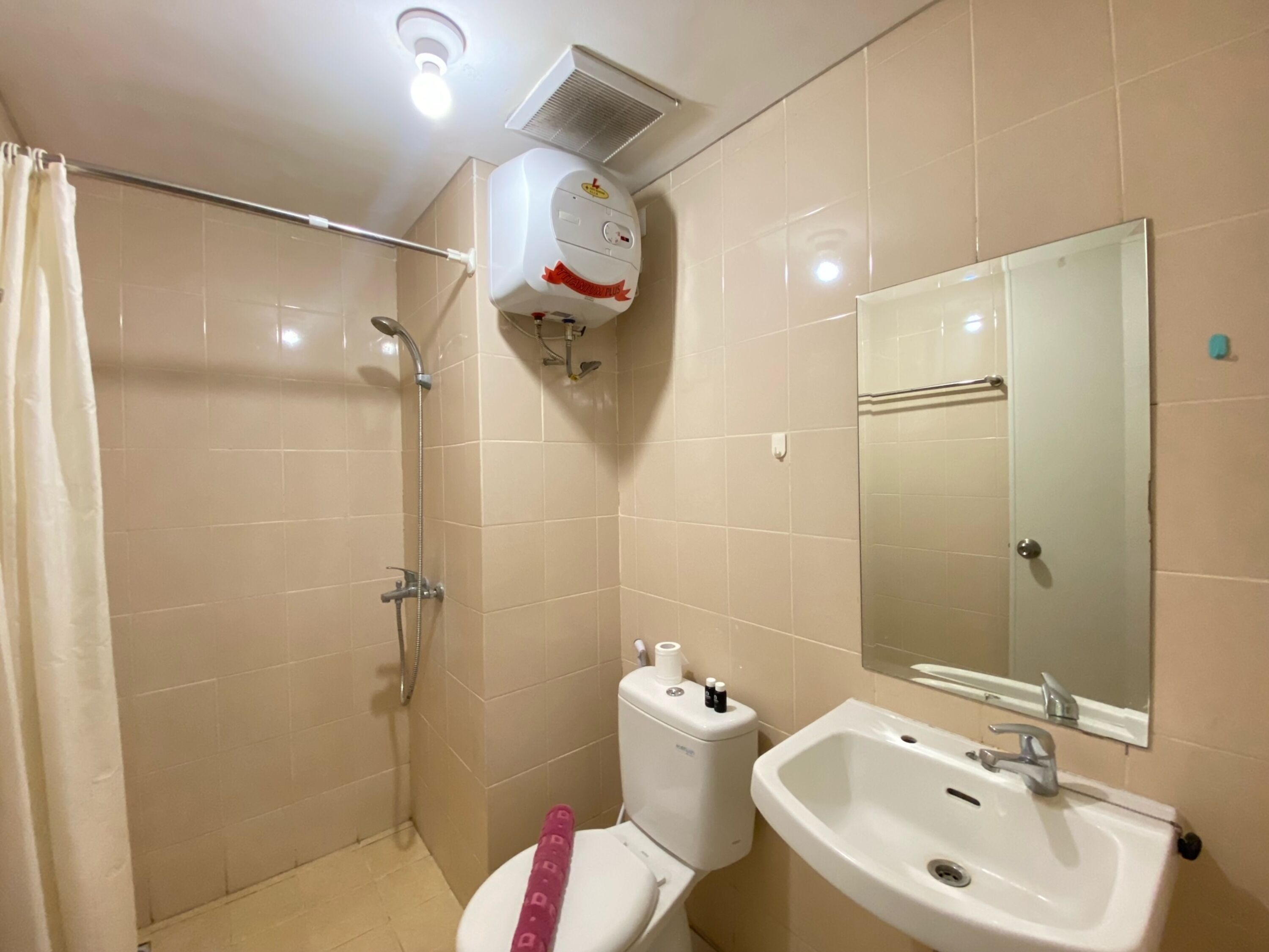 A bathroom with a shower, toilet, sink, and mirror.
