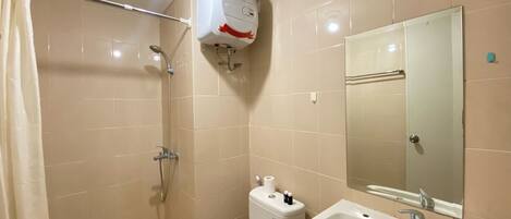 A bathroom with a shower, toilet, sink, and mirror.