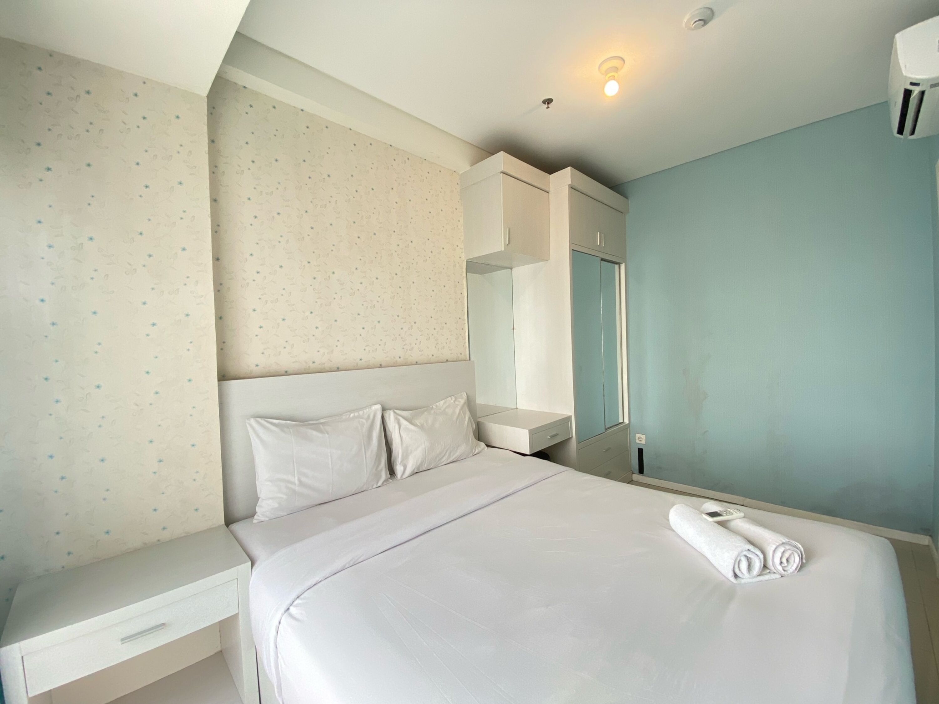 A bedroom with a bed, a nightstand, a wardrobe, and a mirror.