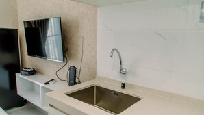 A modern kitchen with a stainless steel sink, a built-in TV, and a white tiled backsplash.