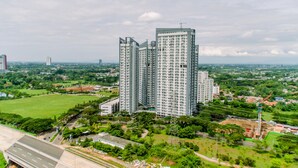 A high-rise building with multiple floors, surrounded by greenery and a highway.