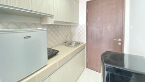 Una cocina compacta con refrigerador, pileta y microondas.