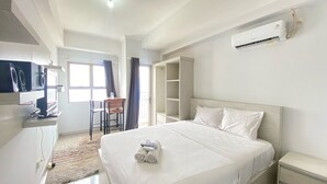 Una habitación de hotel moderna con una cama grande, un escritorio con silla, un armario y un equipo de aire acondicionado.