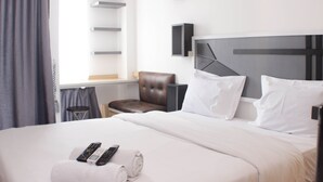 A hotel room with a bed, a chair, a desk, and a window with curtains. - Cozy And Nice Studio At Sayana Bekasi Apartment (Tarumajaya)