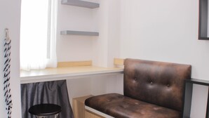 A modern room with a brown leather chair, a small stool, and a white desk with shelves. - Cozy And Nice Studio At Sayana Bekasi Apartment (Tarumajaya)