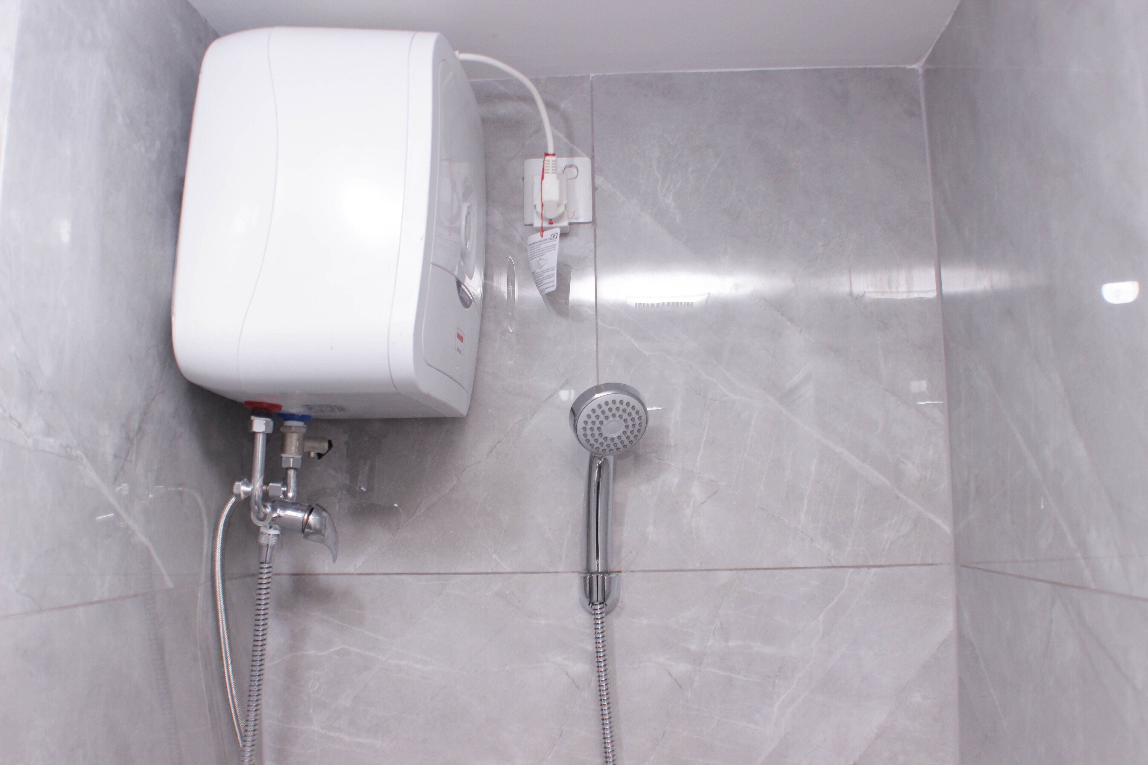 A bathroom with a toilet, a shower, and a wall-mounted water heater.