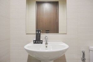 A bathroom with a white sink, a mirror above it, and a wooden door.