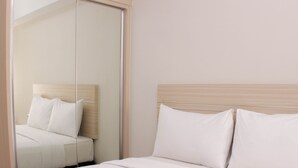A hotel room with a bed, a mirror, and a wooden headboard. - Nice And Comfy 2Br Springlake Apartment Near Summarecon Bekasi (Bekasi)