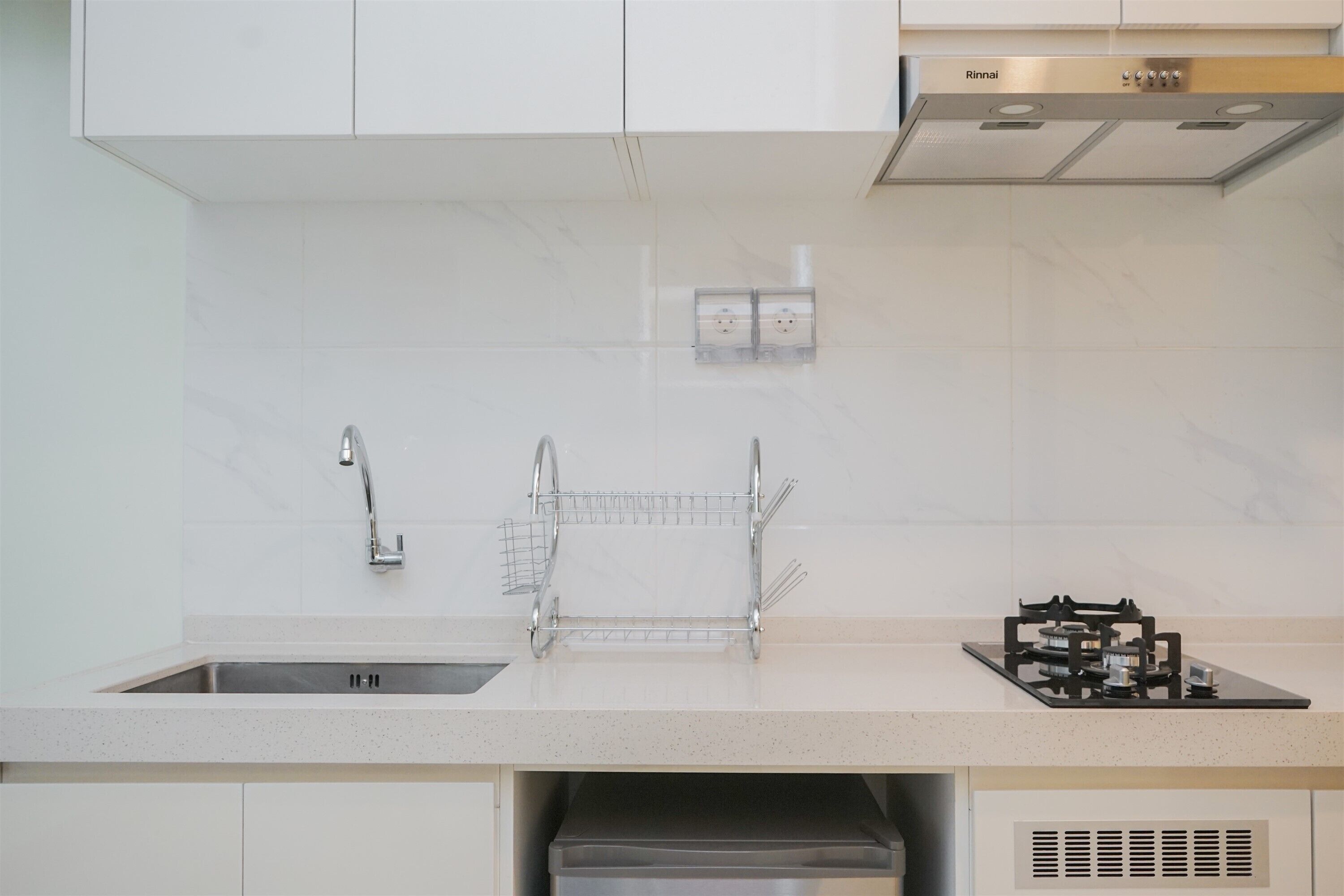 A modern kitchen with a stainless steel sink, a wire rack, and a built-in range hood.
