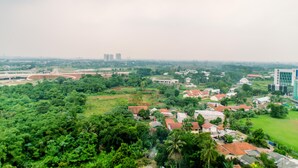 A residential area with houses, a large building, and a highway. - Warm And Cozy Studio Room Apartment At B Residence (Pagedangan)