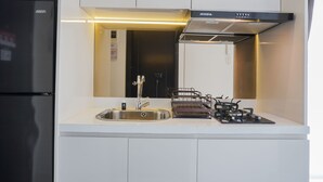 A modern kitchen with a stainless steel refrigerator, a sink, a gas stove, and a hood above the stove. - Elegant And Restful Studio At Casa De Parco Apartment (South Tangerang)