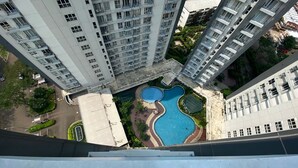 A high-rise building with multiple balconies and a swimming pool complex. - Elegant And Restful Studio At Casa De Parco Apartment (South Tangerang)