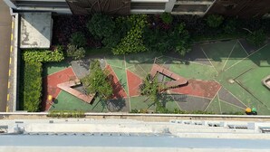 An aerial view of a sports court with multiple colored areas, surrounded by greenery and a building structure. - Nice And Cozy Studio Room At Casa De Parco Apartment (Pagedangan)