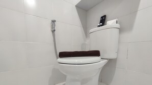A white toilet with a brown seat cover in a bathroom with white tiled walls and floor.