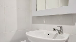 A white bathroom sink with a chrome faucet and a mirror above it.