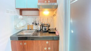 A compact kitchen with wooden cabinets, a black countertop, and a built-in oven. - Minimalist And Nice 1Br At Gateway Pasteur Apartment (Cimahi)