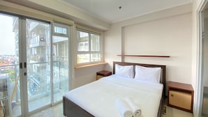 A bedroom with a large bed, two nightstands, a wooden headboard, and a view through a sliding glass door to an outdoor balcony. - Minimalist And Nice 1Br At Gateway Pasteur Apartment (Cimahi)