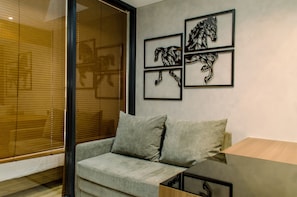 Un salon moderne avec un canapé gris, une table basse en bois et trois œuvres d’art abstraites représentant des chevaux, encadrées et accrochées au mur.