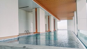 A modern indoor swimming pool with a wooden ceiling and glass walls. - Elegant And Nice 1Br At The Smith Alam Sutera Apartment (Tangerang)