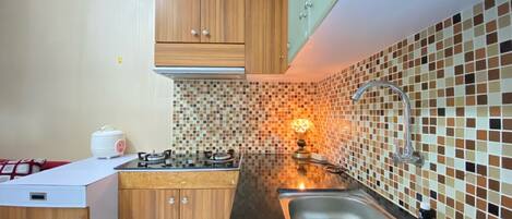 A kitchen with wooden cabinets, a tiled backsplash, a sink, and a stove.