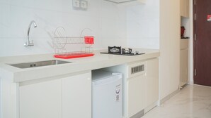 Una cocina moderna con armarios blancos, un lavamanos de acero inoxidable y un lavavajillas compacto.