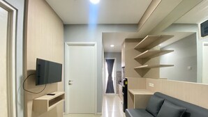 Un salon moderne doté d’un téléviseur à écran plat fixé au mur, d’un canapé et d’étagères intégrées.