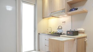A modern kitchen with wooden cabinets, a built-in stove, and a small island with a kettle.