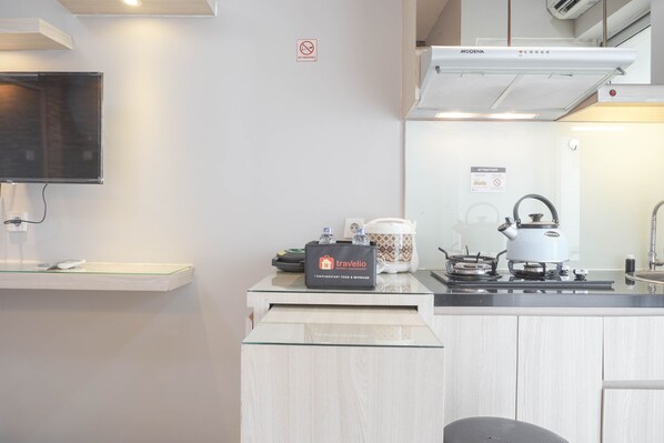 Una cocina moderna con televisión de pantalla plana, una bolsa de viaje, un hervidor y una estufa.