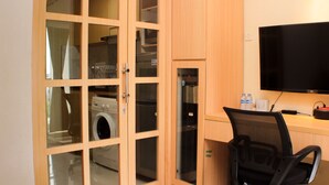 Una habitación con lavadora, refrigerador, televisor y una silla.