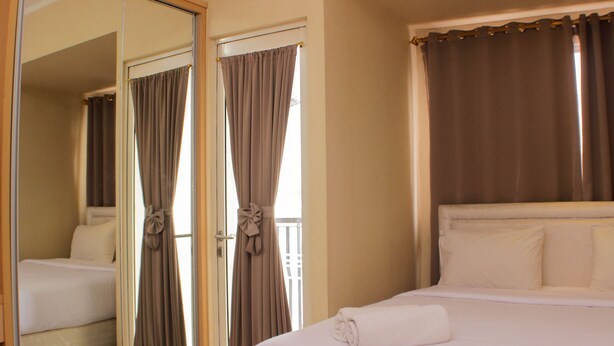 Una habitación de hotel con cama, espejo y cortinas.